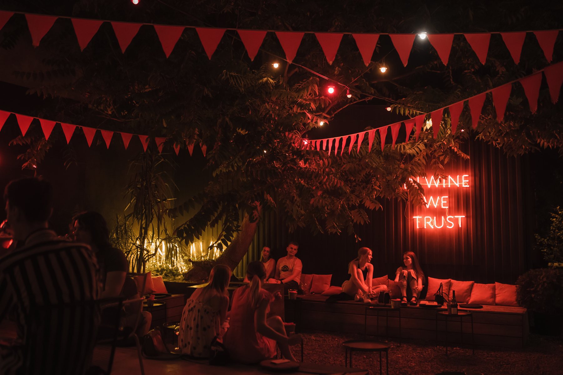 Вечерний двор бара Сияние с гирляндами и неоновой надписью In wine we trust