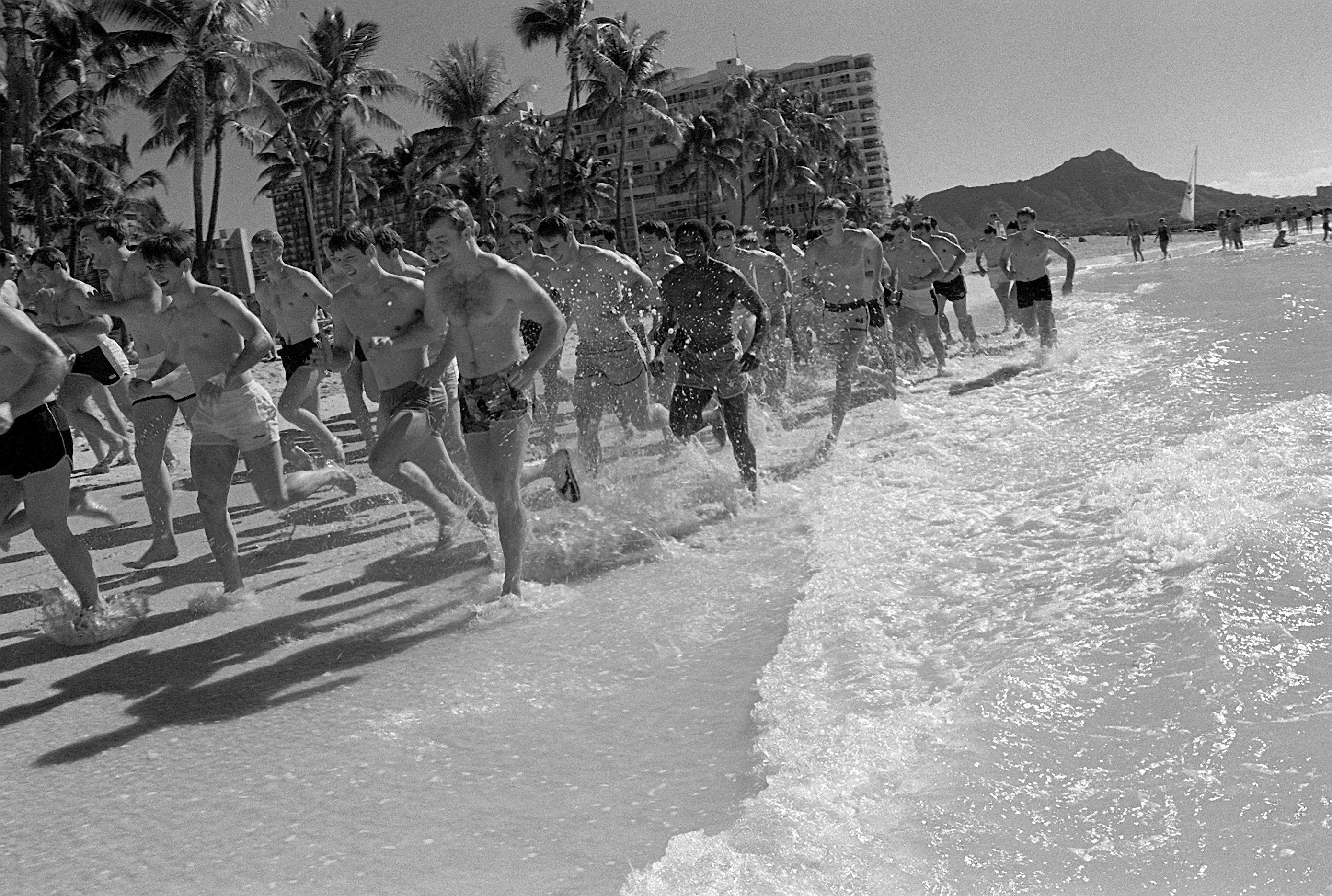 Спортсмены бегут босиком вдоль кромки воды на пляже Вайкики в 1980 году